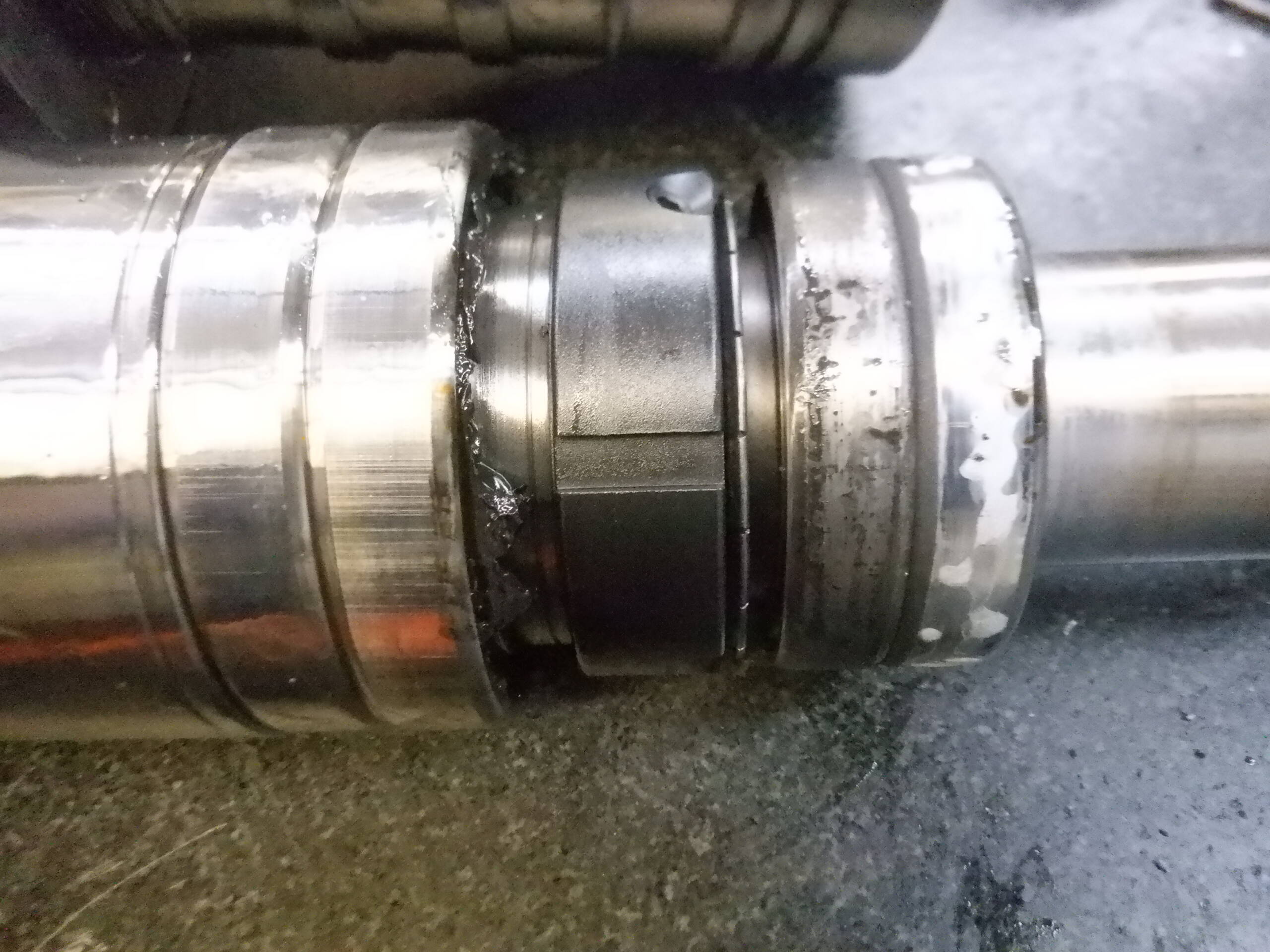 Close-up of a metal pipe joint with multiple bands and visible wear or corrosion.