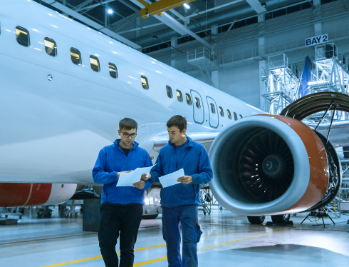 Men walking through an airplane hangar beside a parked airplane